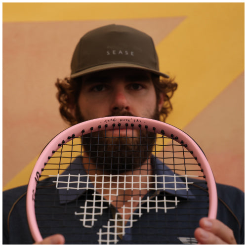 Player holding the pink ART x TENNIS TF-40 in front of a painted backdrop